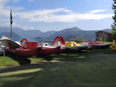 Pedalò colorati allineati sulla riva di un lago montano.