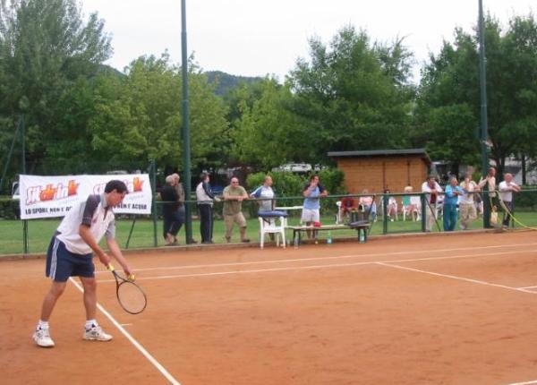 Giocatore di tennis in campo con pubblico sullo sfondo.